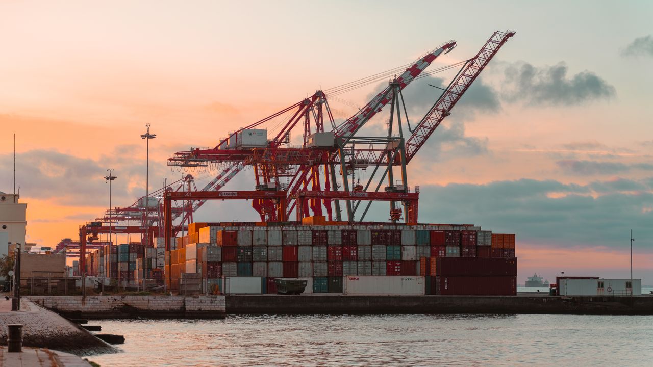 Avance à l'importation : grues et conteneurs dans un port au coucher du soleil